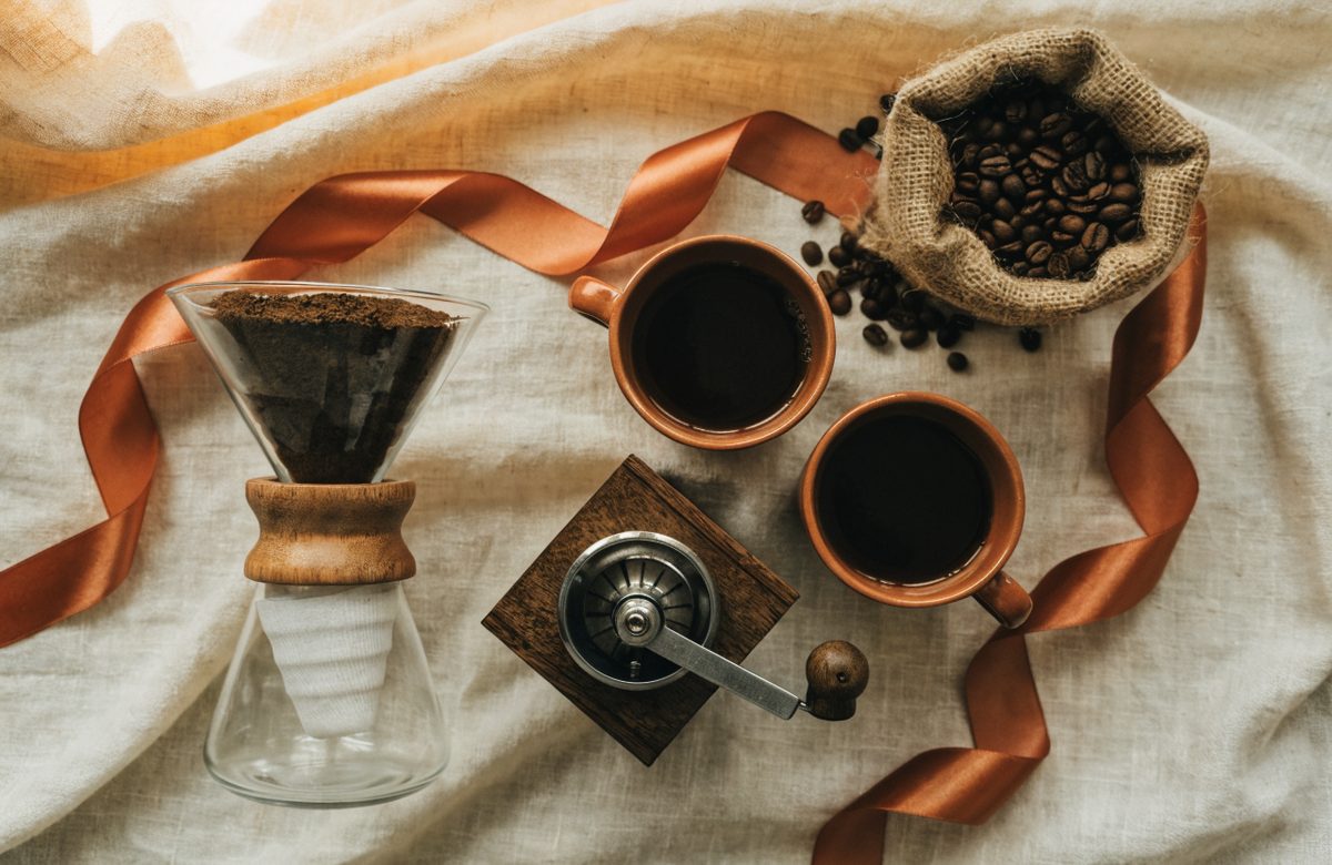 Geschenkarrangement für Kaffeetrinker mit Handmühle, Handfilter und Tassen auf Cremeleinen