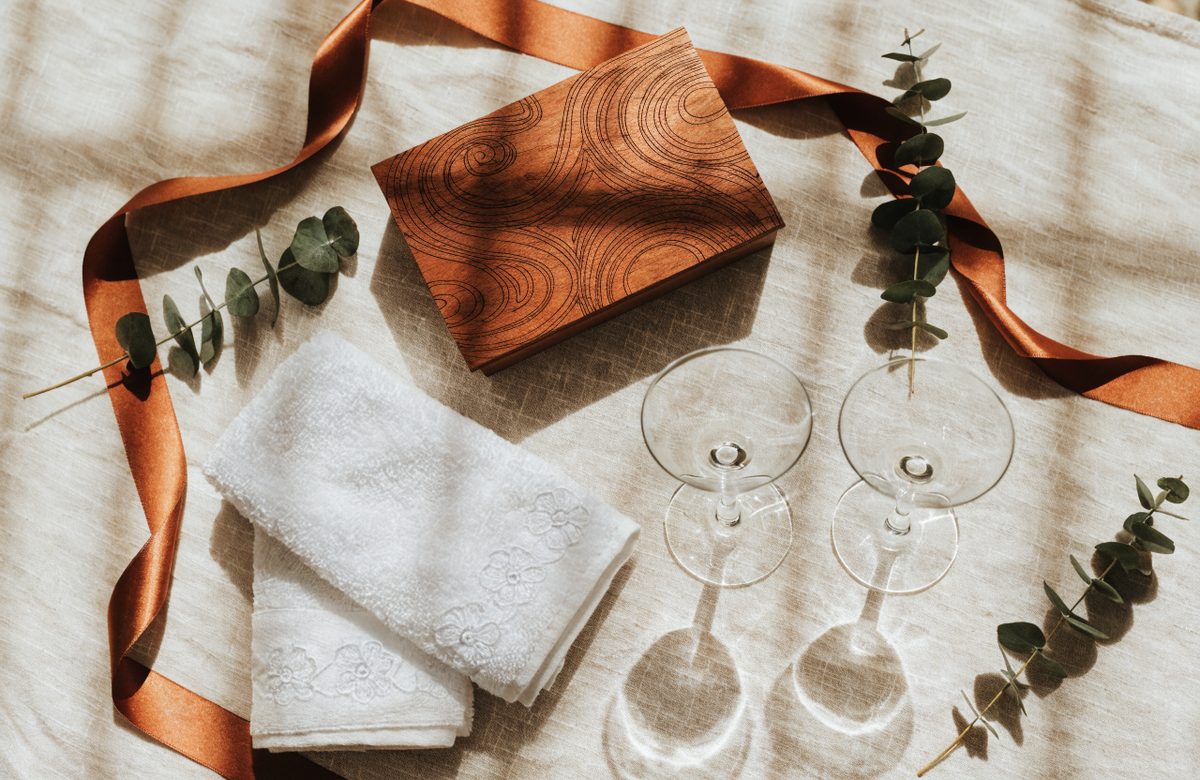Personalisierte Hochzeitsgeschenke mit gravierter Holzbox, Sektgläsern und Eukalyptus auf Cremeleinen